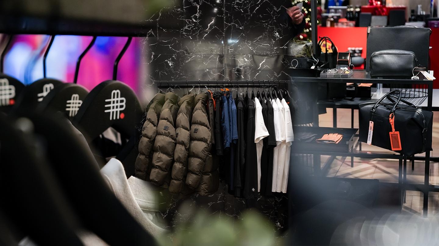 Detailansicht eines Gebauer und Gebauer Pop-up Stores mit schwarzen Ledertaschen, Kleidung, Jacken und orangefarbenen Akzenten