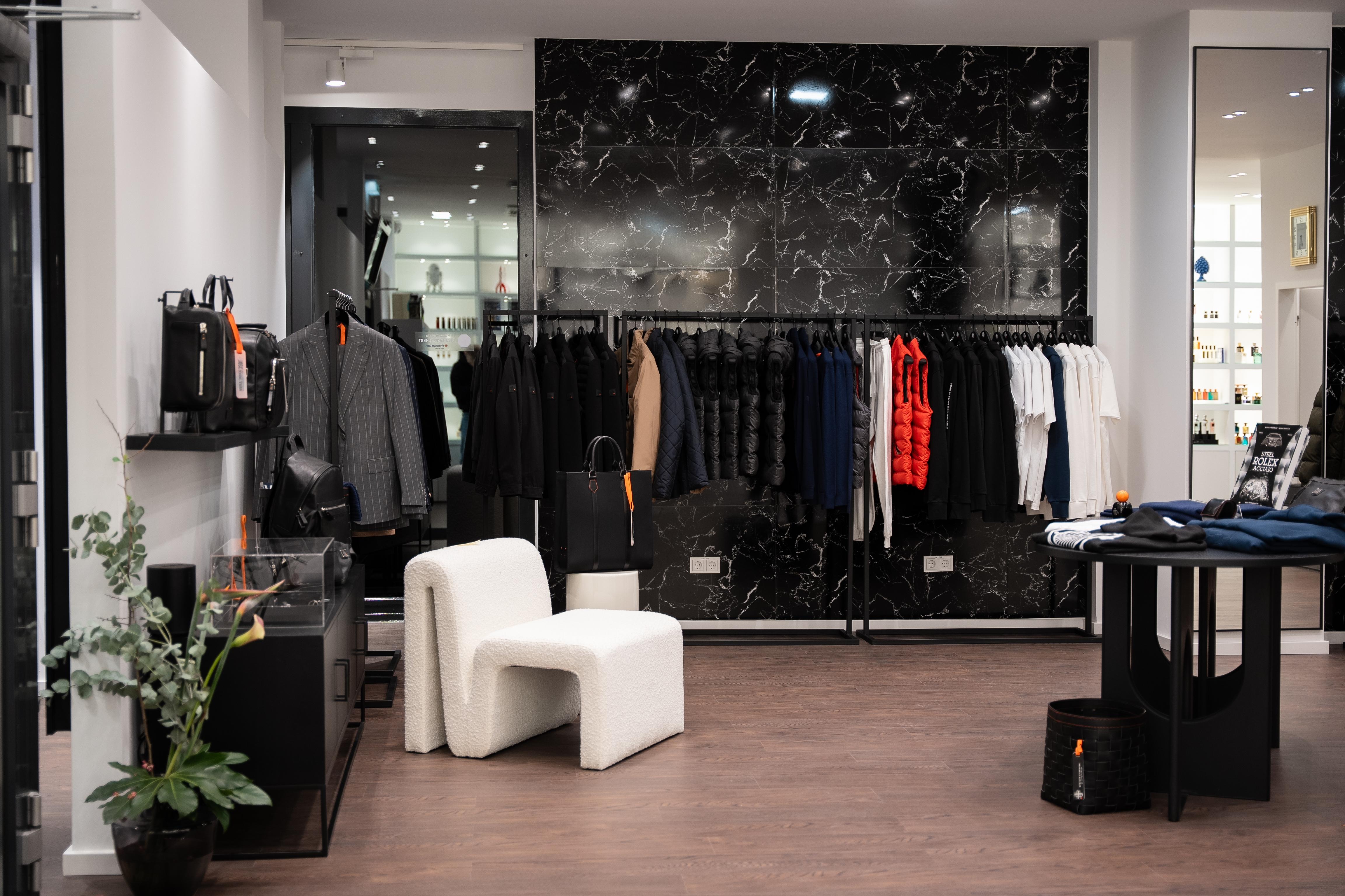 Gebauer und Gebauer Pop-up Store mit Kleidung, schwarzer Ledertasche, Lederaccessoires und Präsentationsfläche vor schwarzer Marmorwand